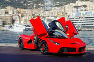 紅色法拉利 LaFerrari 在海濱打開車門，靠近遊艇和城市。 — MacBook 壁紙