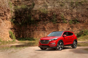 紅色現代 Tucson SUV 停泊在池塘附近，後面有岩石懸崖。 — Surface Pro 壁紙