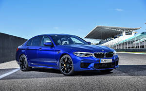 藍色BMW M5房車停在賽道上，看台可見。 — 藍色 壁紙