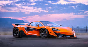 橙色McLaren P1超級跑車在暮色中的沙漠公路上，背景有山脈 — 麥拿侖 GIF 壁紙