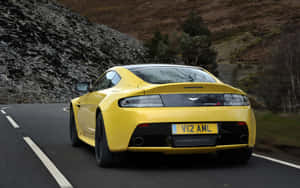 黃色 Aston Martin V12 Vantage S 在日落時分行駛於山路 — Steam Deck OLED 壁紙