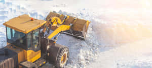 黃色除雪推土機在明亮的冬日陽光下清理積雪。 — 超寬螢幕 壁紙
