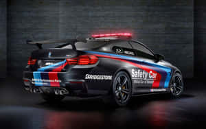 黑色BMW M4安全車，帶有紅、藍色塗裝和閃爍的燈光，停在黑暗的車庫中。 — MacBook Pro 13 壁紙