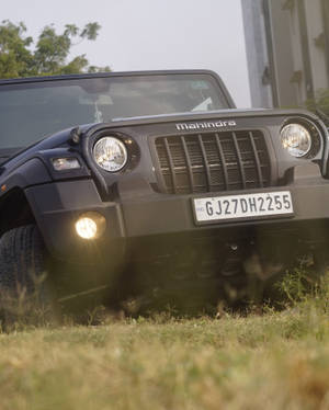黑色Mahindra Thar SUV停在草地上，車頭燈亮起。 — 草 壁紙