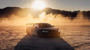 黑色跑車在金色日落和塵雲中於沙漠飄移。 — Audi R8 GIF 壁紙