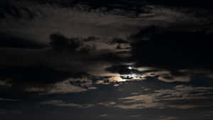 月光穿透烏雲，映照出戲劇性的夜空。 — 夜空 壁紙