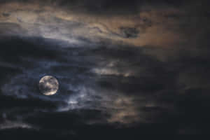 滿月穿過夜間的烏雲照耀。 — 月色夜空 壁紙