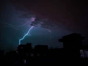 閃電擊中暴風雨夜空下黑暗的城市屋頂。 — 雷暴 壁紙