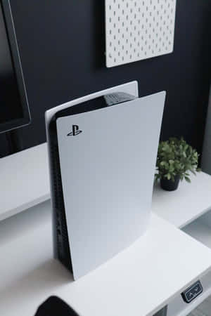 白色 PlayStation 5 主機放在乾淨的白色桌子上，附近有一棵小植物。 — Huawei MatePad Air (2026) 壁紙