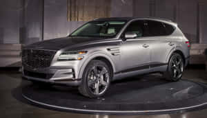 展廳旋轉展示平台上的銀色 Genesis GV80 SUV。 — 酷車 壁紙