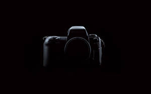 一部黑色Nikon F100相機機身置於黑暗中央，帶有微妙高光。 — 暗色 壁紙