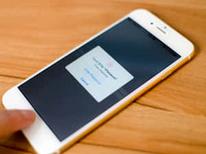手指懸停在iPhone Touch ID上方，在木桌上解鎖裝置 — 手機鎖定螢幕 壁紙