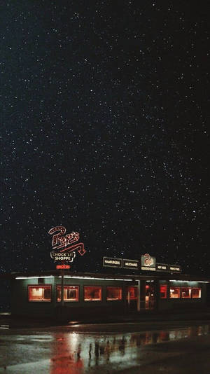 一間復古餐廳在星空下，濕漉漉的路面反射著它的燈光。 — 星星 壁紙