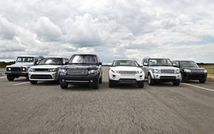 六輛 Land Rover SUV 在陰天的道路旁並排停放。