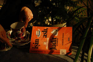 一隻手拿著一個花卉圖案的茶杯，旁邊放著一本書名為 Işın Aslı Judit 的書。 — 書籍 壁紙