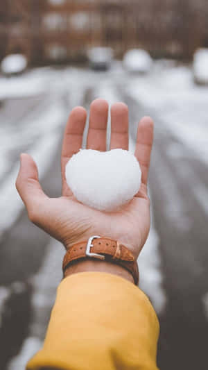 在積雪的都市街道上，手拿著心形雪球。 — 低調 壁紙