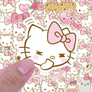 手拿著帶有粉紅色蝴蝶結的Hello Kitty貼紙，置於圖案背景上。 — Hello kitty 美學 GIF 壁紙
