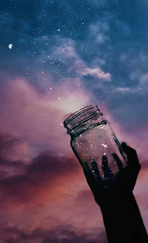 手拎住罐喺帶有新月嘅暮色天空下捕捉流星。 — Galaxy Tab S9 FE 壁紙