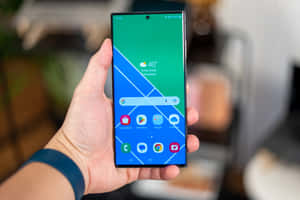 手拿著智能手機，顯示色彩繽紛的幾何屏幕。 — Samsung S23 Ultra 壁紙