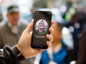 手拿著手機，顯示人臉識別設置畫面，展示微笑的男士和指示。 — iPhone 鎖定畫面 GIF 壁紙