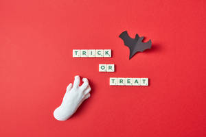 萬聖節 trick or treat 用 Scrabble 字母磚和紙蝙蝠拼寫在紅色背景上。 — 萬聖節 壁紙