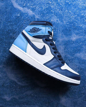 在有紋理的藍色背景上，一雙藍色、白色和海軍藍的 Air Jordan 運動鞋。 — Jordan 標誌 GIF 壁紙
