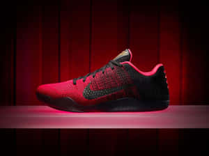 紅黑配色的Nike Kobe籃球鞋在木質舞台上被粉紅光芒照亮。 — 4:3 壁紙