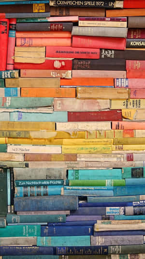 牆上覆蓋著色彩繽紛的復古書籍，可見書名和磨損的書脊。 — 書籍 壁紙