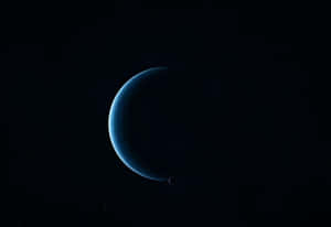 一顆藍色新月形行星帶著一顆小衛星在繁星點點的夜空中運行。 — 行星 壁紙
