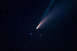 一顆帶有發光尾巴的彗星在佈滿星星的夜空中閃耀。 — 月色夜空 壁紙