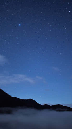 剪影山脈在星空夜空下從霧氣中升起。