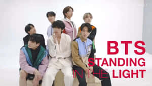 BTS 七位成員在攝影棚內擺姿勢，背景上有粗體紅色文字寫著 BTS STANDING IN THE LIGHT。 — 明亮 壁紙