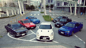 六輛經典和現代的日產跑車停放在城市廣場上。 — 天際線 壁紙