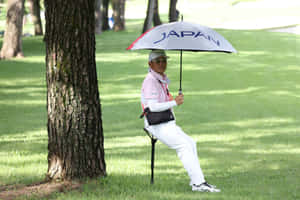高爾夫球手在高爾夫球場的樹旁，在Japan雨傘下休息。