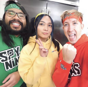 三位微笑的朋友穿著相配的Spy Ninjas連帽衫在廚房裡擺姿勢。 — 微笑 壁紙