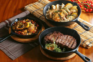三個鑄鐵煎鍋，裝有牛排、雞肉和炒菜，放在木桌上，配有竹蓆和紅莓。 — MacBook Air 13 壁紙