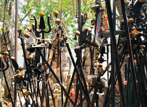 一個神聖的花園，充滿金屬柱、鈴鐺和金色球體，在明亮的陽光下。