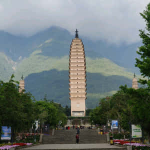 一座高塔被樹木和山巒環繞，人們在階梯上行走。 — 建築 壁紙