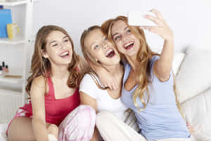 三位微笑的年輕女性在沙發上一起自拍。