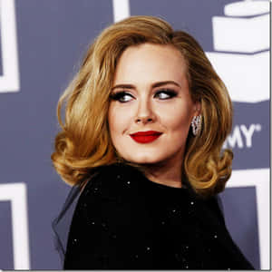 Adele 在葛萊美獎活動中穿著黑色閃亮連衣裙和紅唇。