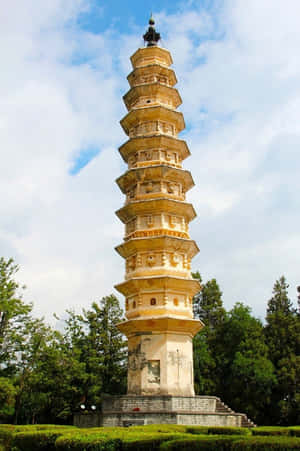 古老石塔被綠樹環繞，在部分多雲的天空下。 — 建築 壁紙