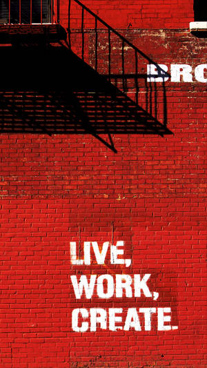 紅色磚牆上帶有白色文字 live work create 和黑色防火梯陰影。
