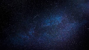 銀河系在深藍色中閃耀，繁星點點，一顆流星劃過夜空。