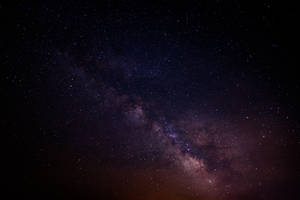 銀河系在黑暗的夜空中閃爍著紫色和粉紅色的星星。