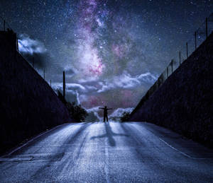 人在路上張開雙臂站在銀河夜空下