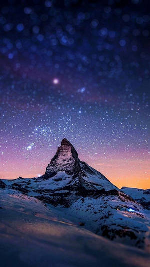 在紫色和橙色色調的星空暮色天空下，白雪覆蓋的山峰。 — 三星 Galaxy S20 壁紙