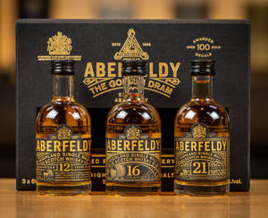 三瓶Aberfeldy威士忌，年份分別為12年、16年和21年，在她們的黑色盒子前。