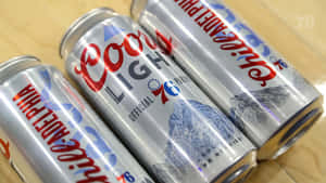 三個帶有費城76人標誌的Coors Light啤酒罐放在木頭上。