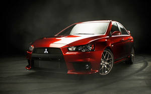 紅色三菱Lancer Evolution跑車在攝影棚中，有煙霧和聚光燈。