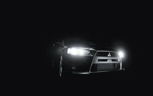 黑色跑車在黑暗背景下亮起車頭燈。